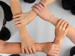 Foto von fünf Händen, die sich jeweils an den Armen halten